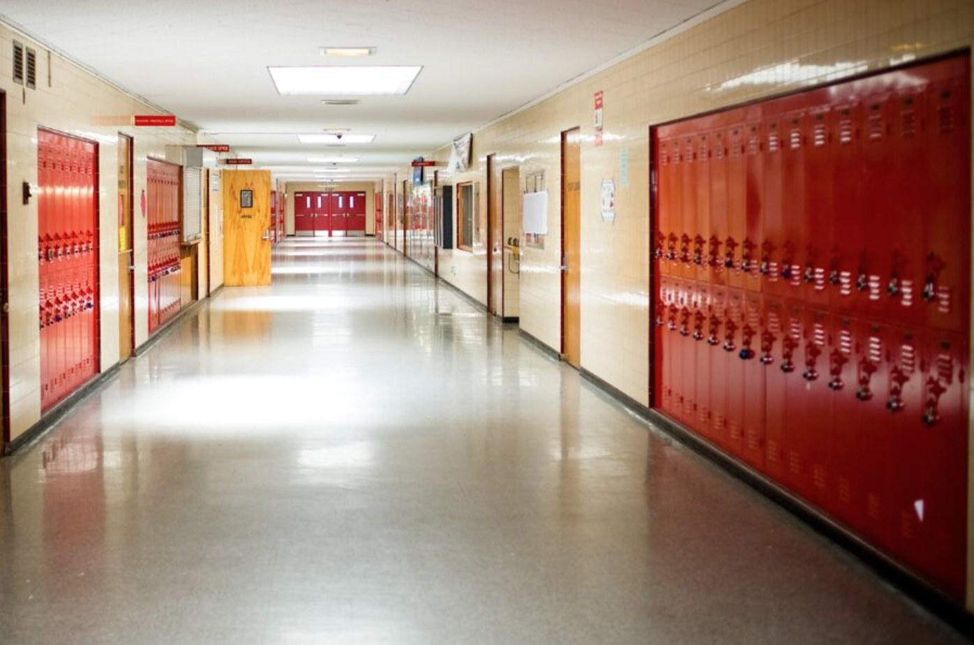 An empty high school hallway with lockers on both sides of the wall